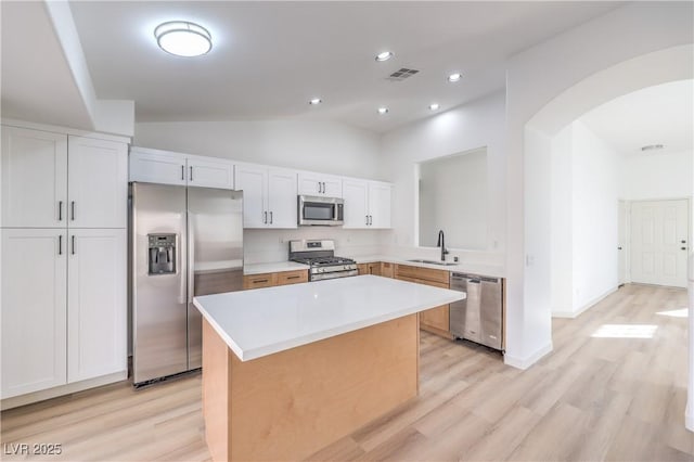 7021 Feather Pine St, Las Vegas, NV 89131 - kitchen featuring stainless steel appliances, arched walkways, light wood-style floors, a kitchen island, and lofted ceiling