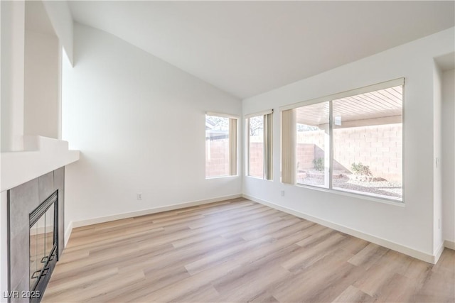 7021 Feather Pine St, Las Vegas, NV 89131 - unfurnished living room featuring vaulted ceiling, healthy amount of natural light, light wood-type flooring, and a tile fireplace