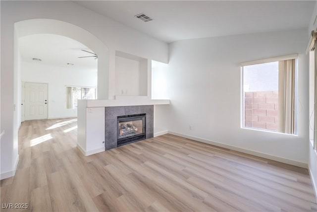 7021 Feather Pine St, Las Vegas, NV 89131 - unfurnished living room featuring a fireplace, light wood finished floors, arched walkways, and a ceiling fan