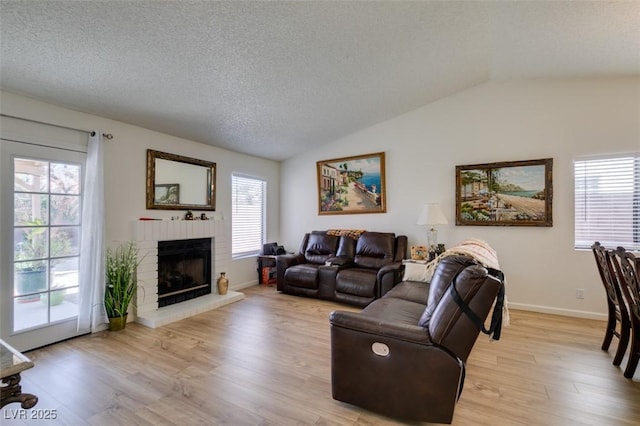 368 Umbria Way, Henderson, NV 89014 - living room with a brick fireplace, vaulted ceiling, light wood-type flooring, and a textured ceiling