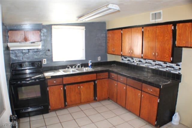 192 W Alma Ave, Overton, NV 89040 - kitchen with electric range, under cabinet range hood, brown cabinetry, light tile patterned floors, and backsplash