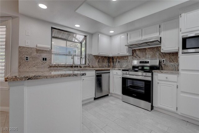 1516 Frandosa Ln, Las Vegas, NV 89117 - kitchen featuring appliances with stainless steel finishes, under cabinet range hood, white cabinetry, light stone countertops, and tasteful backsplash