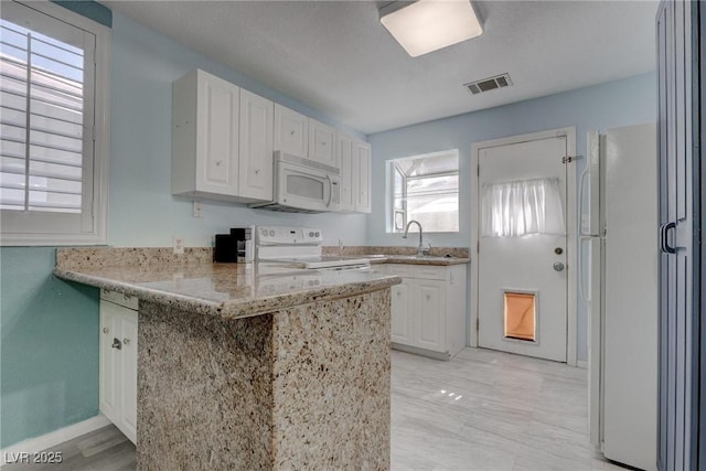 1516 Frandosa Ln, Las Vegas, NV 89117 - kitchen with white appliances, a peninsula, white cabinetry, and light stone counters
