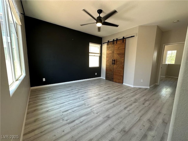 7537 Brisa Del Mar Ave, Las Vegas, NV 89179 - unfurnished bedroom featuring a barn door, multiple windows, wood finished floors, and a ceiling fan