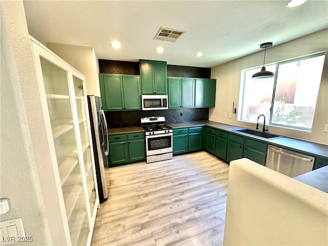 7537 Brisa Del Mar Ave, Las Vegas, NV 89179 - kitchen with green cabinets, stainless steel appliances, light wood finished floors, tasteful backsplash, and pendant lighting