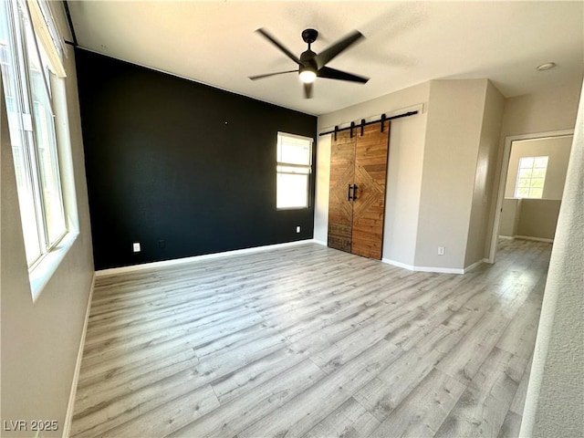 7537 Brisa Del Mar Ave, Las Vegas, NV 89179 - unfurnished bedroom featuring a barn door, multiple windows, wood finished floors, and a ceiling fan