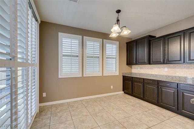 11063 Mount George St, Las Vegas, NV 89179 - kitchen with tasteful backsplash, light tile patterned floors, dark brown cabinetry, light stone countertops, and pendant lighting