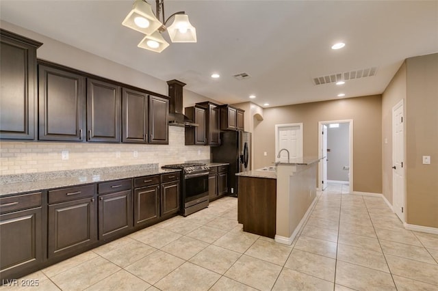 11063 Mount George St, Las Vegas, NV 89179 - kitchen with stainless steel gas stove, wall chimney exhaust hood, tasteful backsplash, light tile patterned floors, and recessed lighting