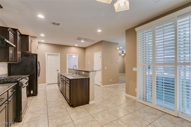 11063 Mount George St, Las Vegas, NV 89179 - kitchen featuring gas stove, dark brown cabinetry, light tile patterned flooring, a kitchen island with sink, and recessed lighting