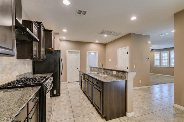 11063 Mount George St, Las Vegas, NV 89179 - kitchen with stainless steel gas range oven, wall chimney exhaust hood, light tile patterned flooring, a kitchen island with sink, and tasteful backsplash
