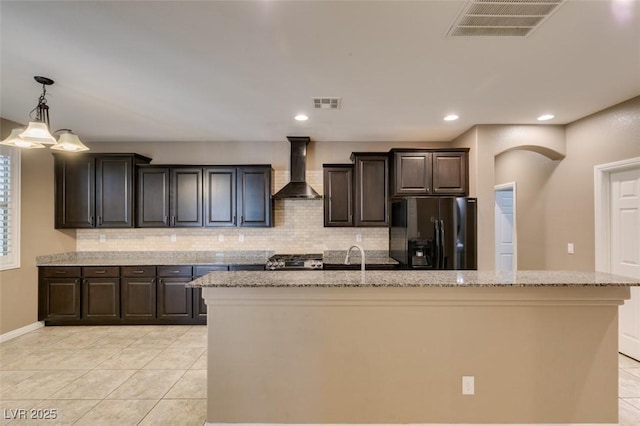 11063 Mount George St, Las Vegas, NV 89179 - kitchen featuring black fridge with ice dispenser, wall chimney range hood, decorative backsplash, a kitchen island with sink, and recessed lighting