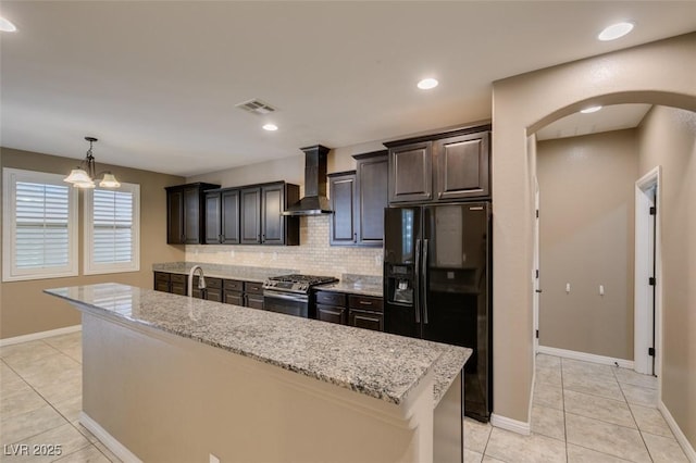 11063 Mount George St, Las Vegas, NV 89179 - kitchen featuring wall chimney exhaust hood, black fridge, gas stove, arched walkways, and backsplash