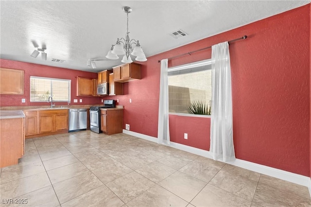 9175 Titan Hill Ct, Las Vegas, NV 89148 - kitchen featuring stainless steel appliances, a textured wall, a textured ceiling, a chandelier, and light tile patterned floors