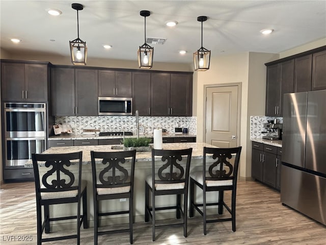 2645 Cava Tirreni St, Henderson, NV 89044 - kitchen featuring appliances with stainless steel finishes, backsplash, dark brown cabinets, light wood-type flooring, and recessed lighting