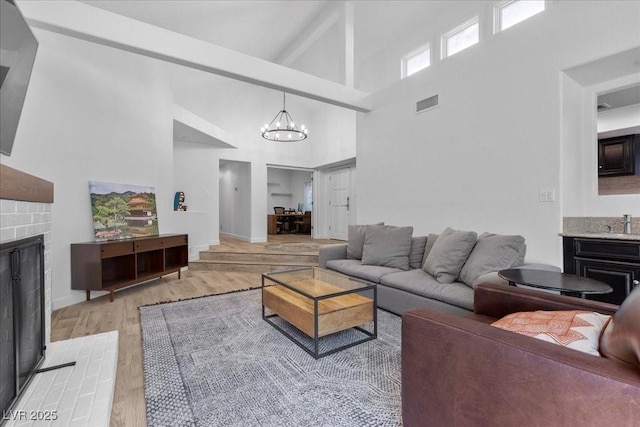7627 Boca Raton Dr, Las Vegas, NV 89113 - living area with high vaulted ceiling, a fireplace, light wood-style flooring, a chandelier, and beam ceiling