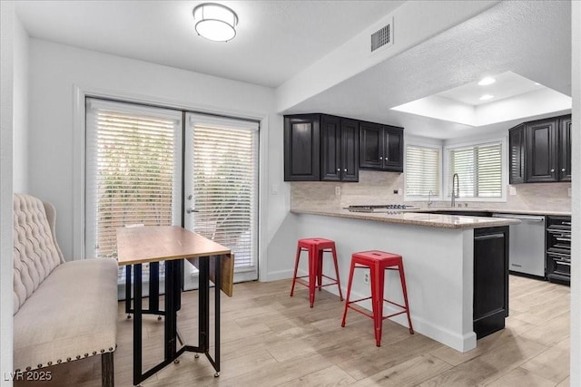 7627 Boca Raton Dr, Las Vegas, NV 89113 - kitchen featuring dark cabinetry, stainless steel dishwasher, a breakfast bar, and backsplash