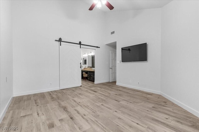 7627 Boca Raton Dr, Las Vegas, NV 89113 - unfurnished living room with ceiling fan, a barn door, light wood finished floors, and high vaulted ceiling