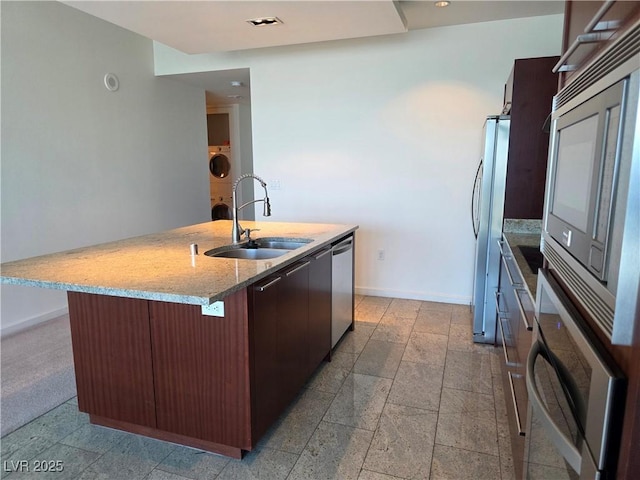 4471 Dean Martin Dr Unit 1104, Las Vegas, NV 89103 - kitchen featuring appliances with stainless steel finishes, stone tile flooring, light stone countertops, a center island with sink, and washer / dryer