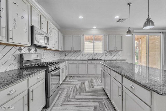 5425 Pride Mountain St, North Las Vegas, NV 89031 - kitchen featuring appliances with stainless steel finishes, crown molding, a center island, tasteful backsplash, and dark stone countertops