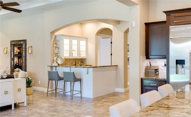 9747 Cathedral Pines Ave, Las Vegas, NV 89149 - kitchen featuring stainless steel fridge with ice dispenser, arched walkways, a ceiling fan, light stone counters, and a breakfast bar area