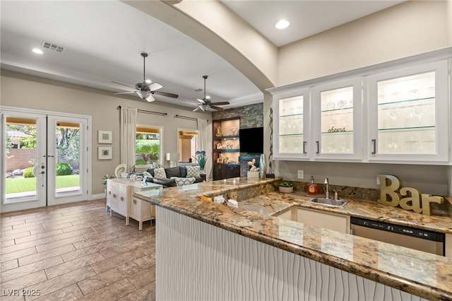 9747 Cathedral Pines Ave, Las Vegas, NV 89149 - kitchen with stainless steel dishwasher, a ceiling fan, light stone counters, glass insert cabinets, and arched walkways