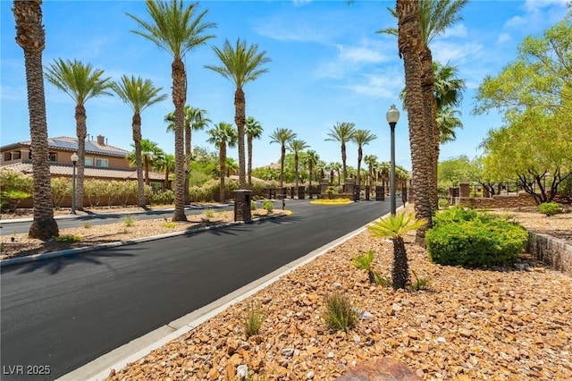 9747 Cathedral Pines Ave, Las Vegas, NV 89149 - view of asphalt road with street lights, curbs, and a gated entry