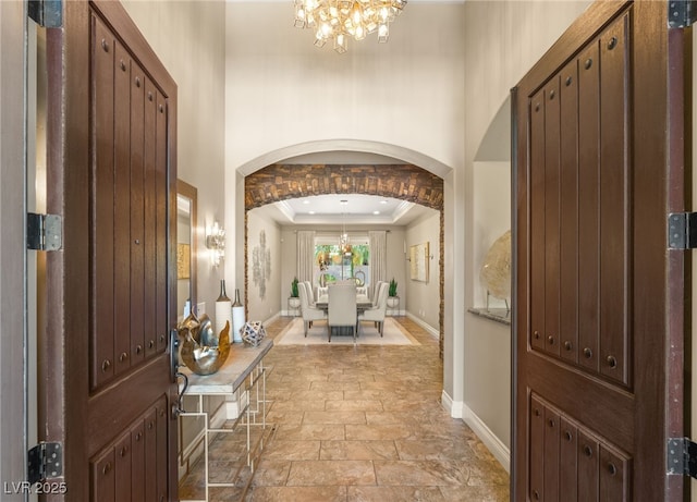 9747 Cathedral Pines Ave, Las Vegas, NV 89149 - foyer with a chandelier, stone tile floors, crown molding, arched walkways, and a tray ceiling