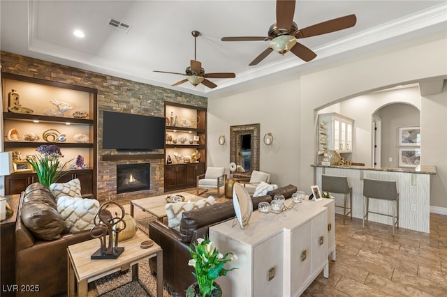 9747 Cathedral Pines Ave, Las Vegas, NV 89149 - living room with arched walkways, a fireplace, a ceiling fan, crown molding, and a raised ceiling
