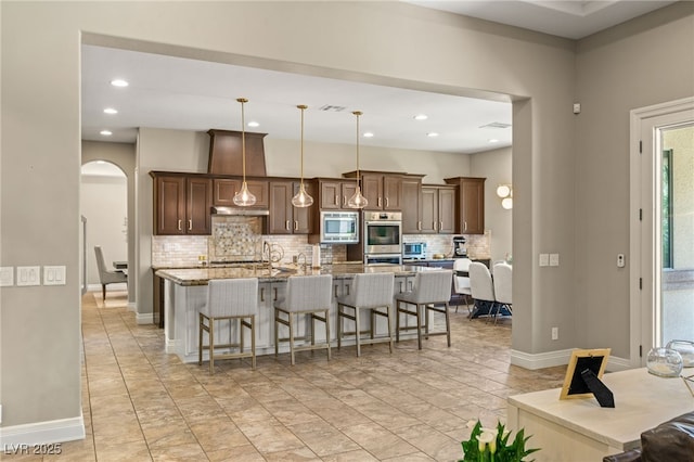 9747 Cathedral Pines Ave, Las Vegas, NV 89149 - kitchen with stainless steel appliances, arched walkways, decorative backsplash, a breakfast bar area, and recessed lighting