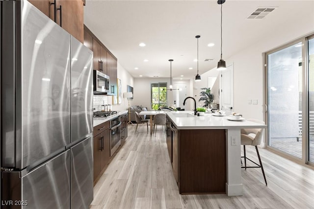 11756 Emerald Lake Ave, Las Vegas, NV 89138 - kitchen with appliances with stainless steel finishes, light wood finished floors, light countertops, a kitchen island with sink, and recessed lighting