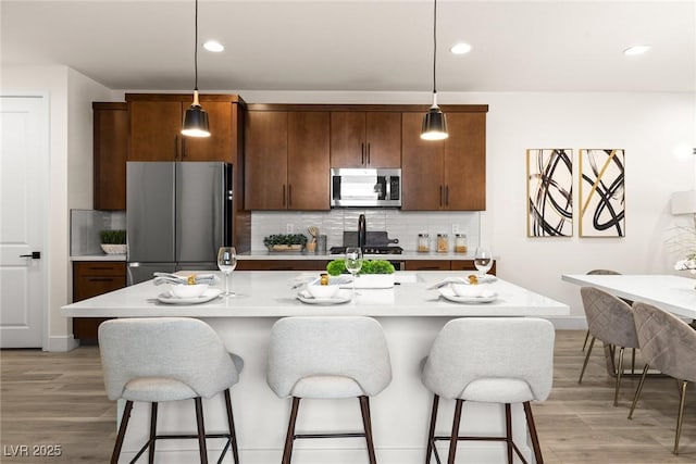11756 Emerald Lake Ave, Las Vegas, NV 89138 - kitchen with stainless steel appliances, light countertops, a kitchen bar, light wood-style flooring, and recessed lighting