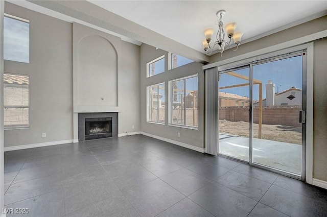 901 Carnival Ave, Las Vegas, NV 89123 - unfurnished living room featuring a chandelier, a tile fireplace, a high ceiling, and dark tile patterned floors