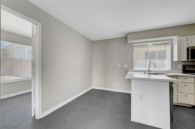 901 Carnival Ave, Las Vegas, NV 89123 - kitchen with stainless steel microwave, light countertops, white cabinetry, stove, and a peninsula