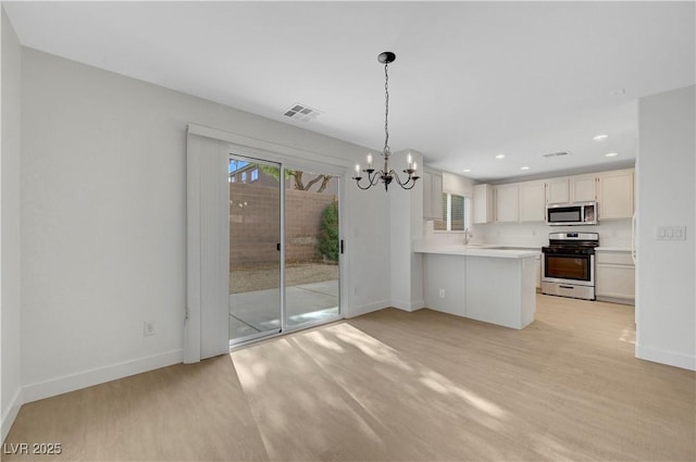 2431 Lilac Cove St, Las Vegas, NV 89135 - kitchen featuring stainless steel appliances, a chandelier, light countertops, a peninsula, and light wood-type flooring