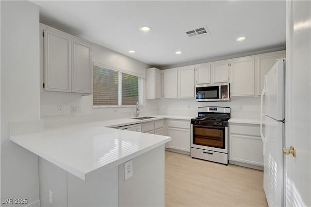 2431 Lilac Cove St, Las Vegas, NV 89135 - kitchen featuring appliances with stainless steel finishes, a peninsula, light countertops, light wood-style flooring, and recessed lighting