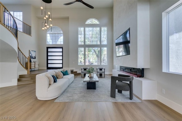 5573 San Florentine Ave, Las Vegas, NV 89141 - living area with stairs, wood finished floors, a towering ceiling, ceiling fan, and a glass covered fireplace
