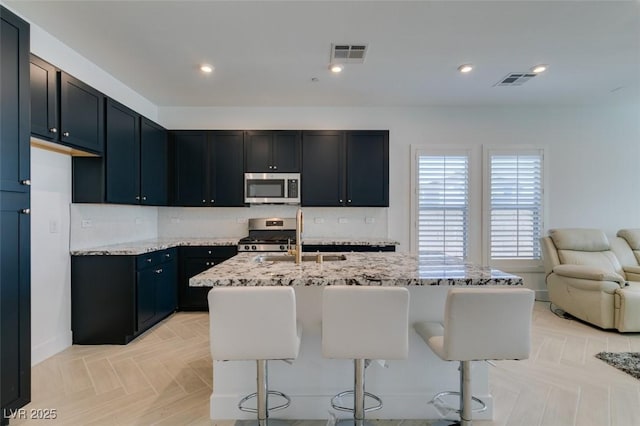 9844 Kings Glen St, Las Vegas, NV 89141 - kitchen with appliances with stainless steel finishes, light stone countertops, a kitchen breakfast bar, backsplash, and open floor plan