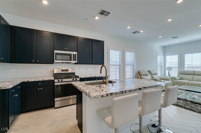 9844 Kings Glen St, Las Vegas, NV 89141 - kitchen featuring stainless steel appliances, light stone countertops, a kitchen island with sink, open floor plan, and recessed lighting