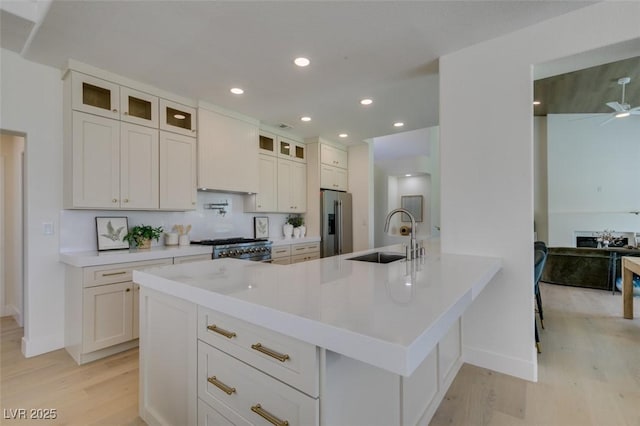 9425 Villa Ridge Dr, Las Vegas, NV 89134 - kitchen featuring light wood finished floors, appliances with stainless steel finishes, glass insert cabinets, a peninsula, and light countertops