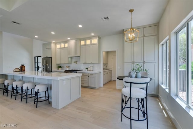 9520 Sundial Dr, Las Vegas, NV 89134 - kitchen featuring a chandelier, light wood-style floors, stainless steel appliances, a kitchen bar, and recessed lighting