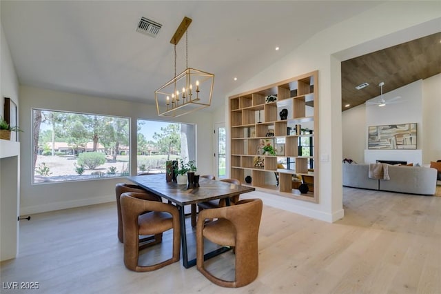 9520 Sundial Dr, Las Vegas, NV 89134 - dining space featuring light wood-style floors, a chandelier, a fireplace, and high vaulted ceiling