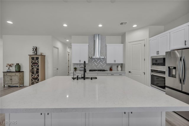5851 Slate Rock Ct, Las Vegas, NV 89149 - kitchen with stainless steel appliances, wall chimney range hood, backsplash, a spacious island, and white cabinets