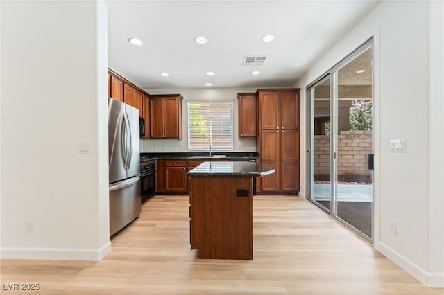 11900 Calle De Sol Dr, Las Vegas, NV 89138 - kitchen with black appliances, light wood-style flooring, a kitchen island, recessed lighting, and dark stone countertops