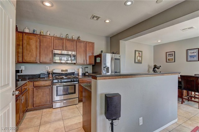 1904 Via Firenze, Henderson, NV 89044 - kitchen with appliances with stainless steel finishes, light tile patterned floors, brown cabinetry, recessed lighting, and a kitchen island
