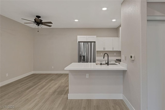 5751 E Hacienda Ave Unit 159, Las Vegas, NV 89122 - kitchen with stainless steel refrigerator with ice dispenser, a peninsula, a ceiling fan, white cabinets, and light wood-style floors