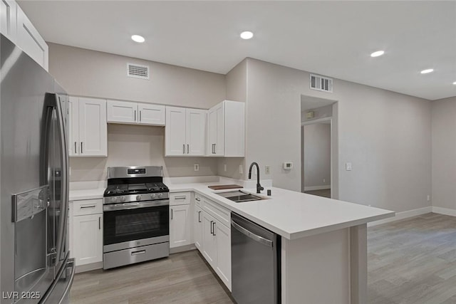 5751 E Hacienda Ave Unit 159, Las Vegas, NV 89122 - kitchen with stainless steel appliances, a peninsula, light wood-type flooring, light countertops, and white cabinetry