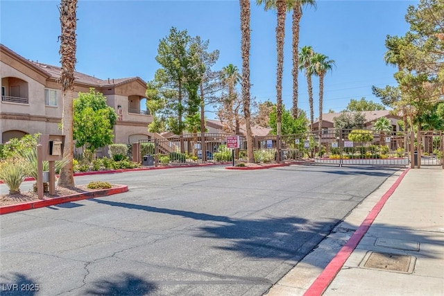 5751 E Hacienda Ave Unit 159, Las Vegas, NV 89122 - view of asphalt road with a gate, curbs, sidewalks, and a gated entry