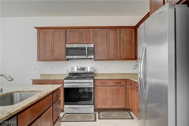 3949 Amanda Bay Ave, North Las Vegas, NV 89081 - kitchen with appliances with stainless steel finishes, light stone countertops, brown cabinetry, and light tile patterned floors