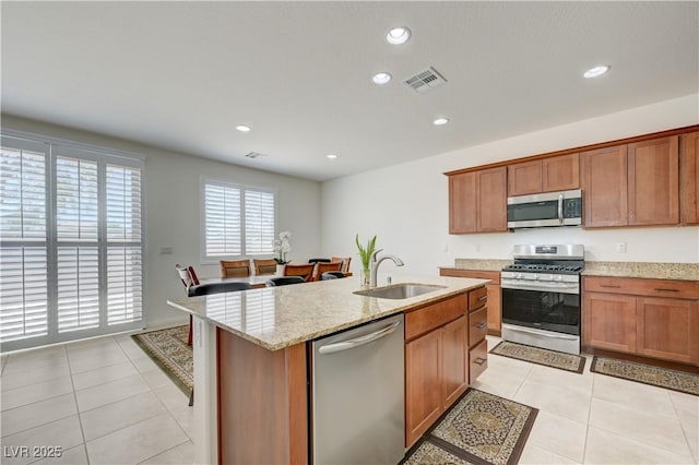 3949 Amanda Bay Ave, North Las Vegas, NV 89081 - kitchen featuring appliances with stainless steel finishes, light tile patterned floors, recessed lighting, light stone counters, and brown cabinets