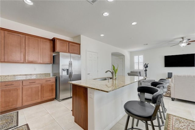 3949 Amanda Bay Ave, North Las Vegas, NV 89081 - kitchen featuring stainless steel refrigerator with ice dispenser, arched walkways, a kitchen breakfast bar, light stone counters, and light tile patterned floors